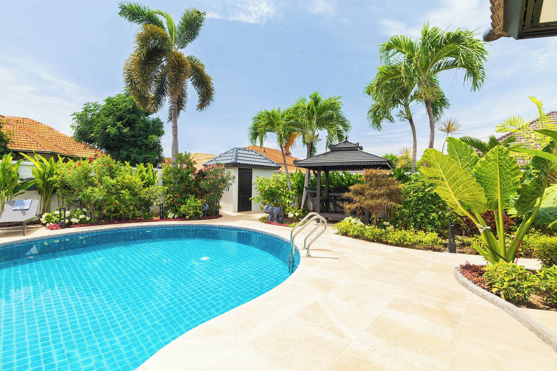 Una piscina rodeada de palmeras y un pabellón.