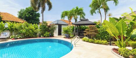 Una piscina rodeada de palmeras y un pabellón.