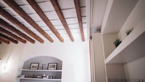 Ein Zimmer mit freiliegenden Holzbalken, einer weißen Wand und einer eingebauten Ablage mit gerahmten Bildern und Dekoration.