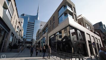Een moderne stadstraat met eigentijdse gebouwen, een opvallend hoog gebouw en voetgangers.