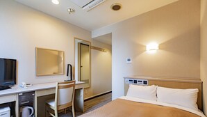 Une chambre d’hôtel équipée d’un lit, d’un bureau, d’une chaise, d’une télévision et d’un miroir.