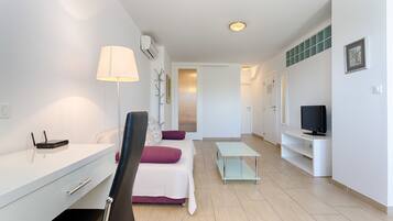 Un salon moderne comprenant un canapé, une table basse, un meuble pour la télévision et un bureau avec une lampe.