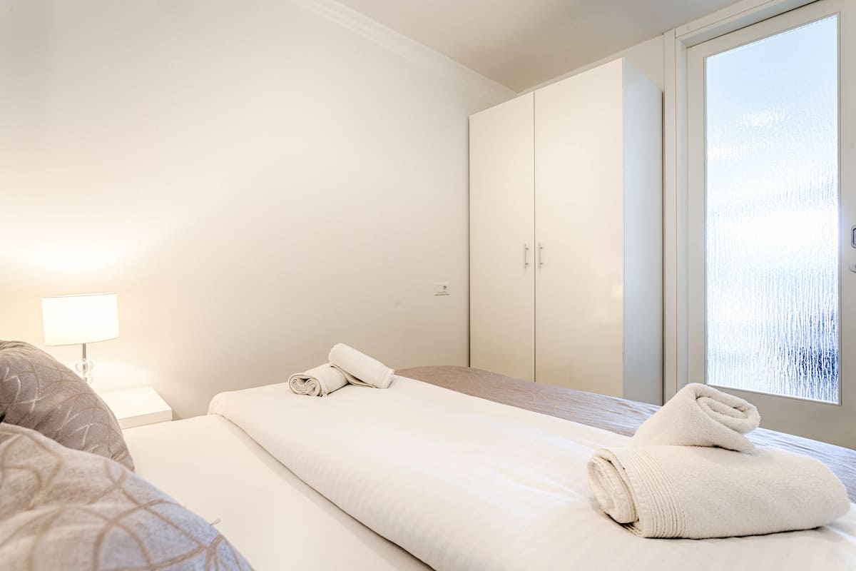 A hotel room with a bed, a nightstand, a window with a view, and a wardrobe.