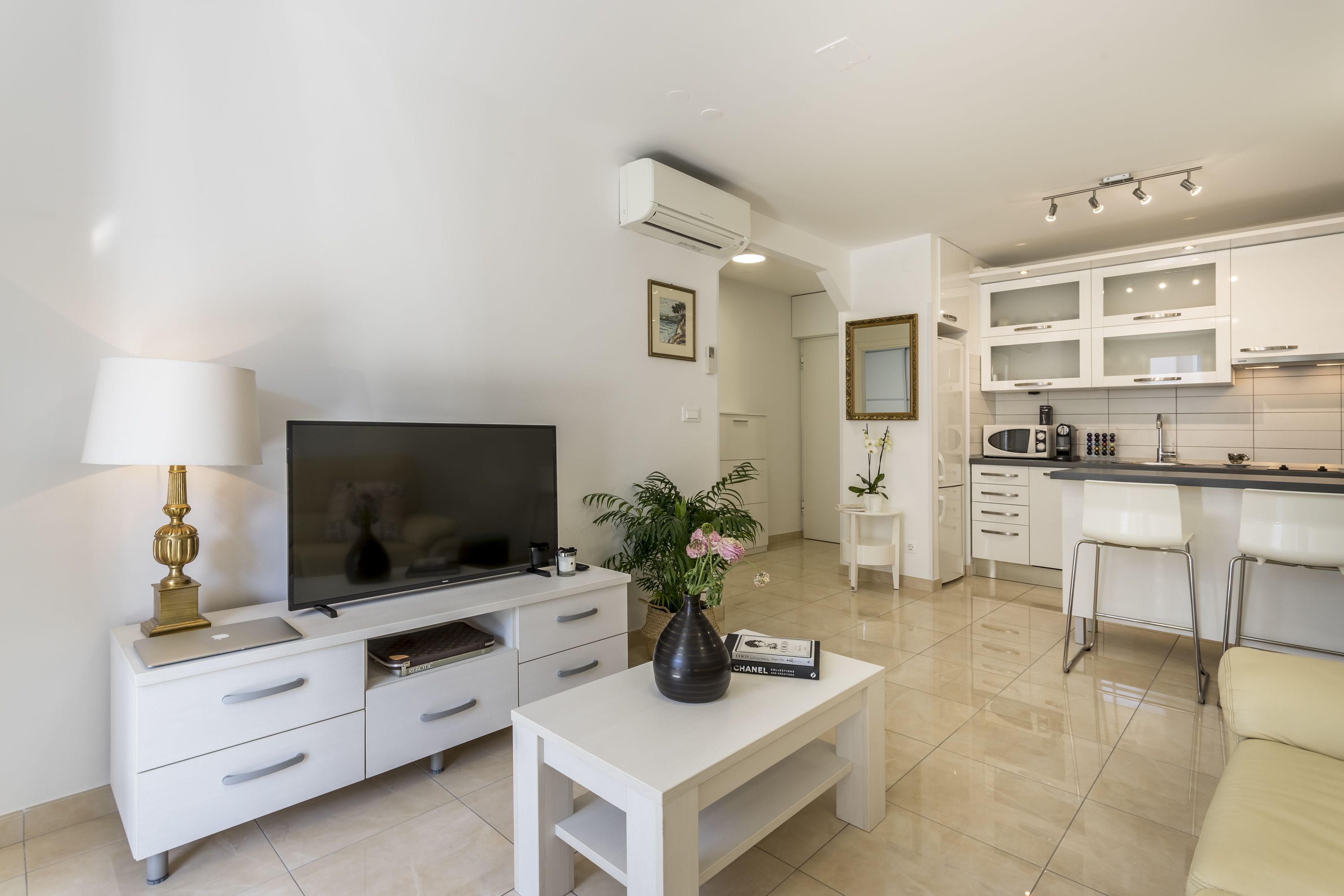 A modern living room with a flat-screen TV, a white coffee table, and a decorative vase.