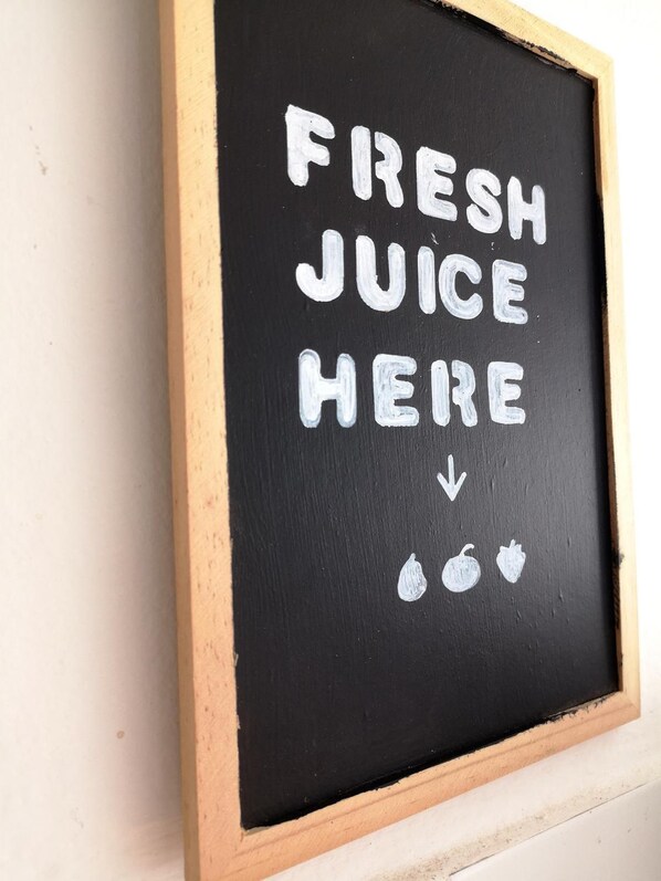 A chalkboard sign with the text "FRESH JUICE HERE" and two apples below it. - Guest House Camilla (Alghero)