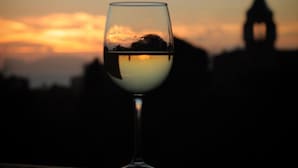 Un verre de vin blanc, avec un coucher de soleil en arrière-plan.