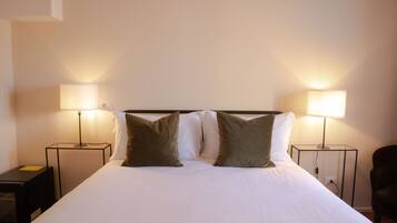 Una habitación de hotel con una cama grande, dos lámparas de noche y una silla.