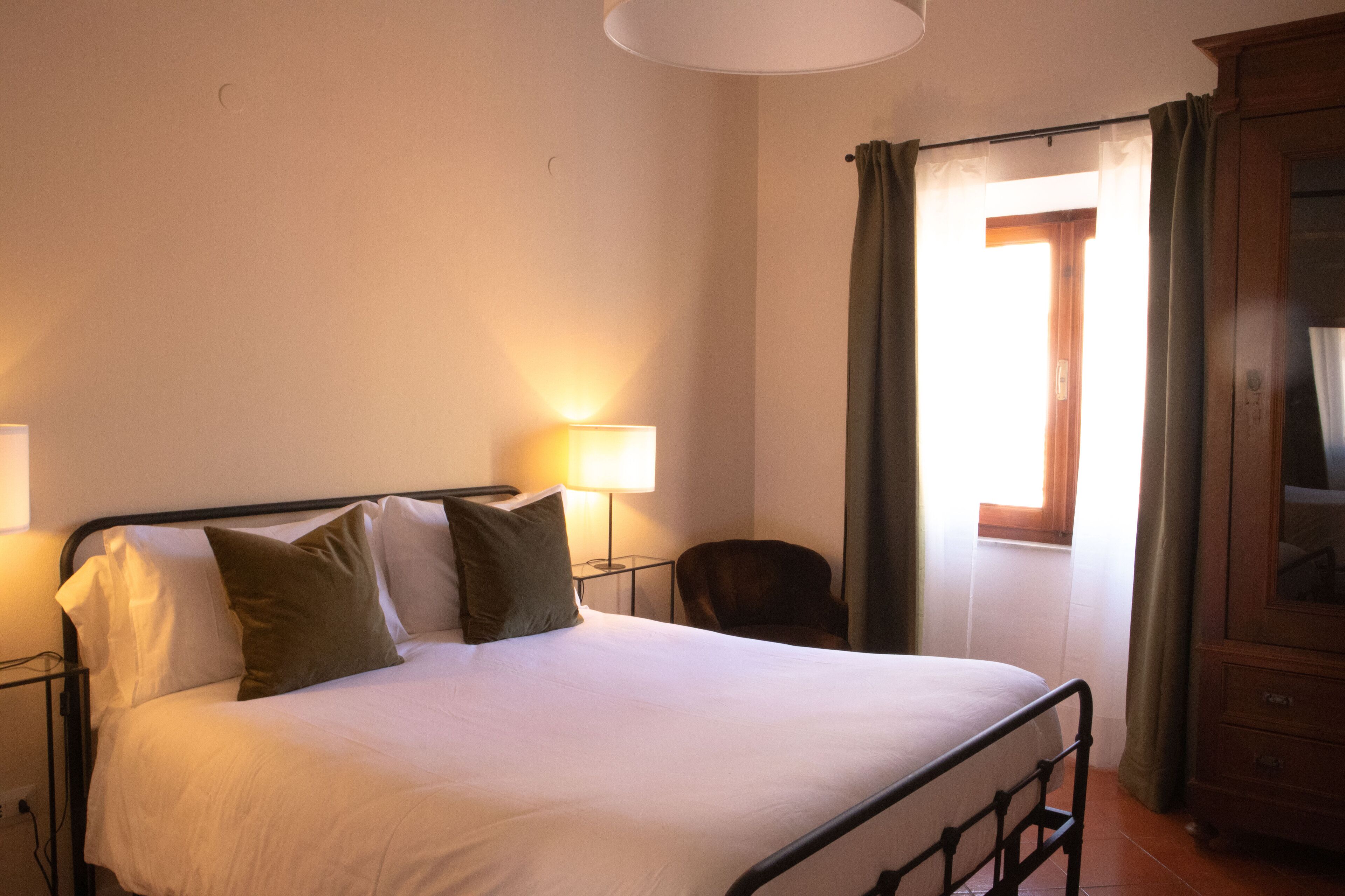 A neatly made bed with pillows, a bedside lamp, and a wooden cabinet.