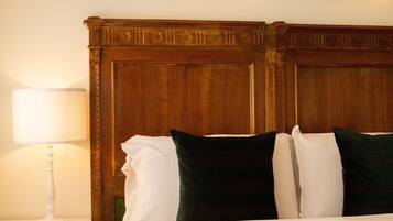 Una cama bien hecha con almohadas blancas y verdes, un cabecero de madera y una lámpara de noche blanca.