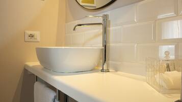 A bathroom with a white sink, chrome faucet, and a mirror above it.