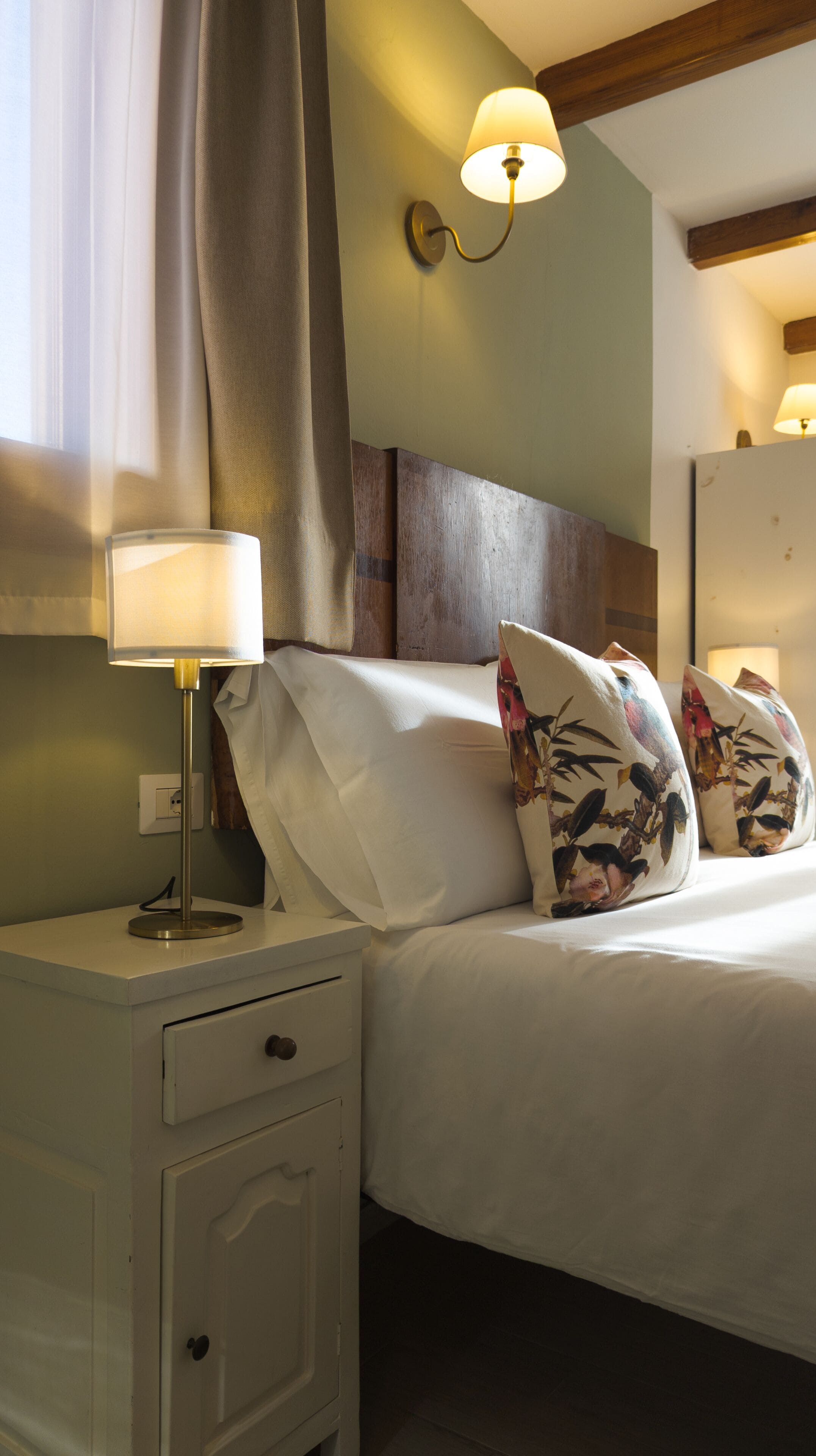 Une chambre à coucher comprenant un lit, une table de chevet, une lampe et un luminaire fixé au mur.