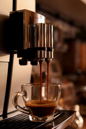 A coffee machine dispensing coffee into a glass cup.