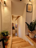 Una scala in legno conduce a una zona cucina con piante in vaso e un quadro appeso al muro.