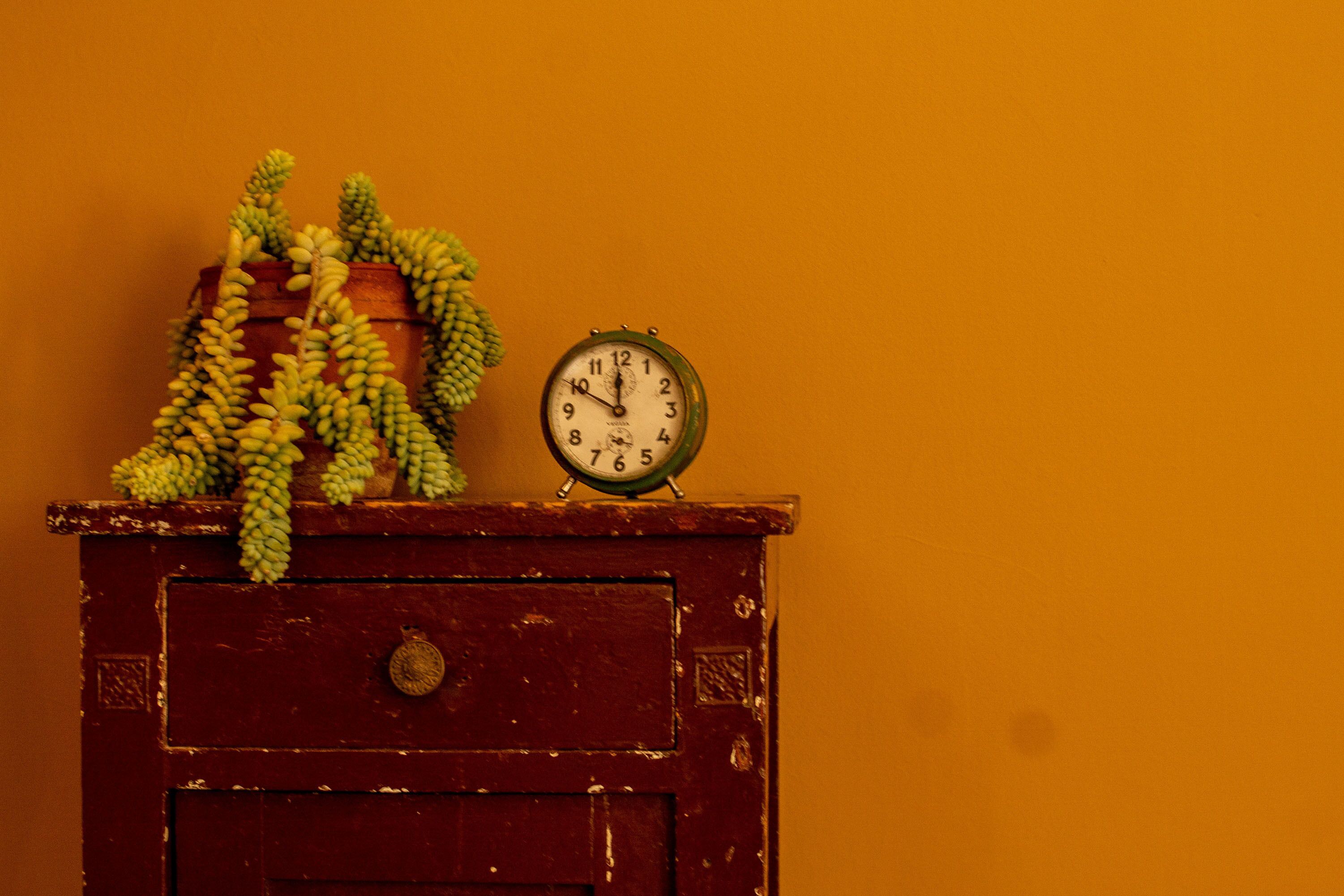 Un aparador de madera con un reloj y un racimo de plátanos encima.