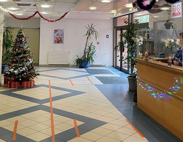 Un vestíbulo con un árbol de Navidad, plantas en macetas y una mesa de recepción.