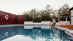 Una piscina con plataforma de baldosas, un flotador salvavidas y una valla.