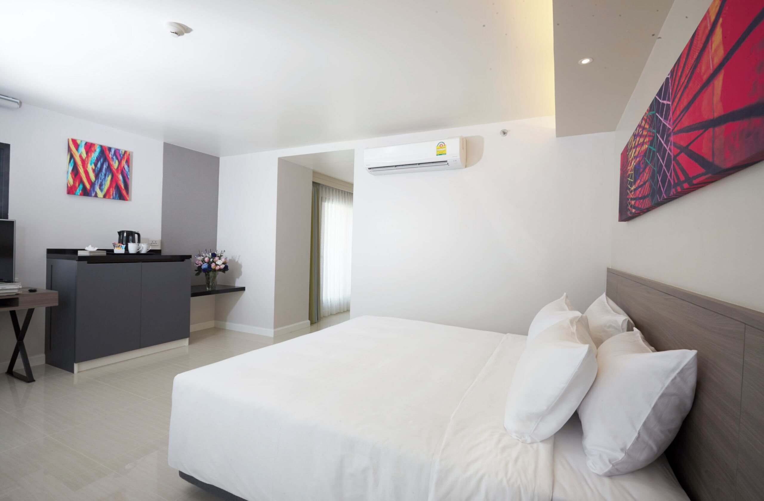 Una habitación de hotel con cama, escritorio, cafetera y un cuadro en la pared.
