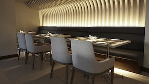 Un comedor moderno con un sofá negro y sillas grises, un techo con estampado y una mesa con menú.