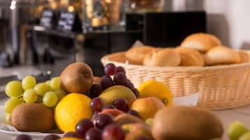A table with a variety of fruits and a basket of bread.