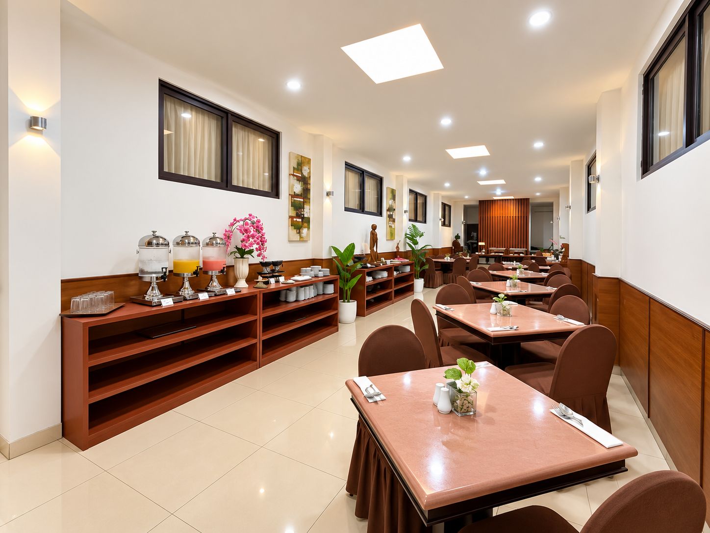Espaço de refeições de hotel com várias mesas e cadeiras, um balcão de buffet e uma janela grande.