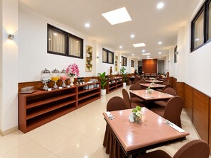 A hotel dining area with multiple tables and chairs, a buffet station, and a large window.