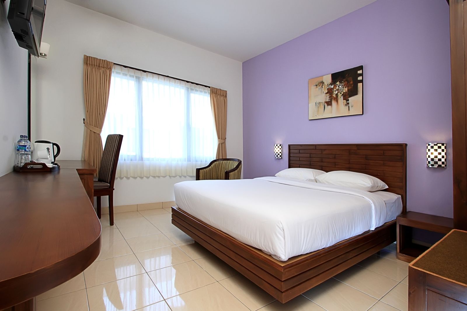 Habitación de hotel con una cama grande, un escritorio, una silla, una ventana con cortinas y un cuadro en la pared.