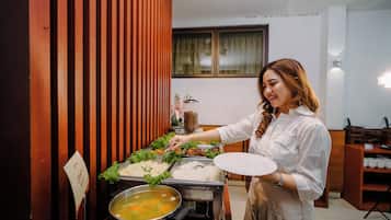A buffet setup with various food items and a person serving.