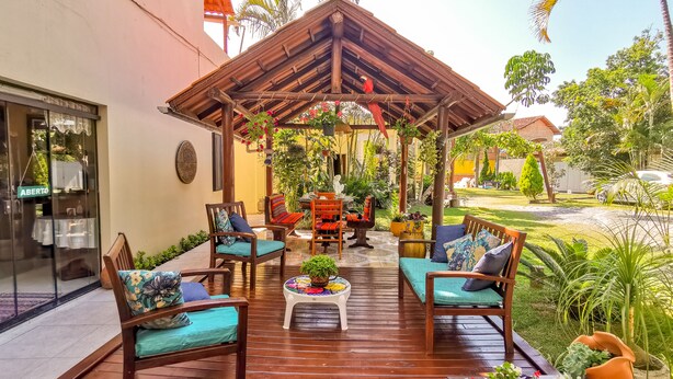 A wooden deck with outdoor furniture, a pergola, and potted plants. - Pousada Magia do Sol (Florianópolis)