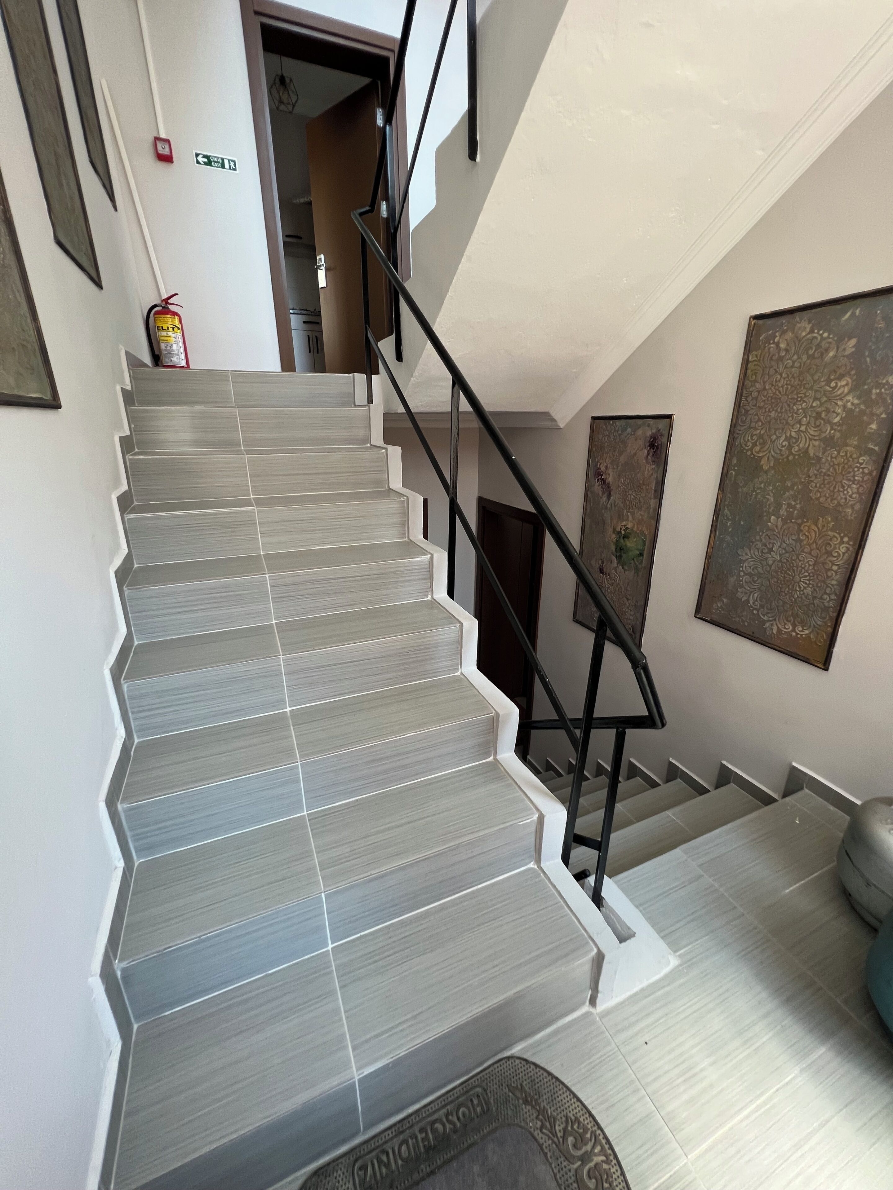 Una escalera de diseño moderno, un extintor y una puerta que da a otra habitación.