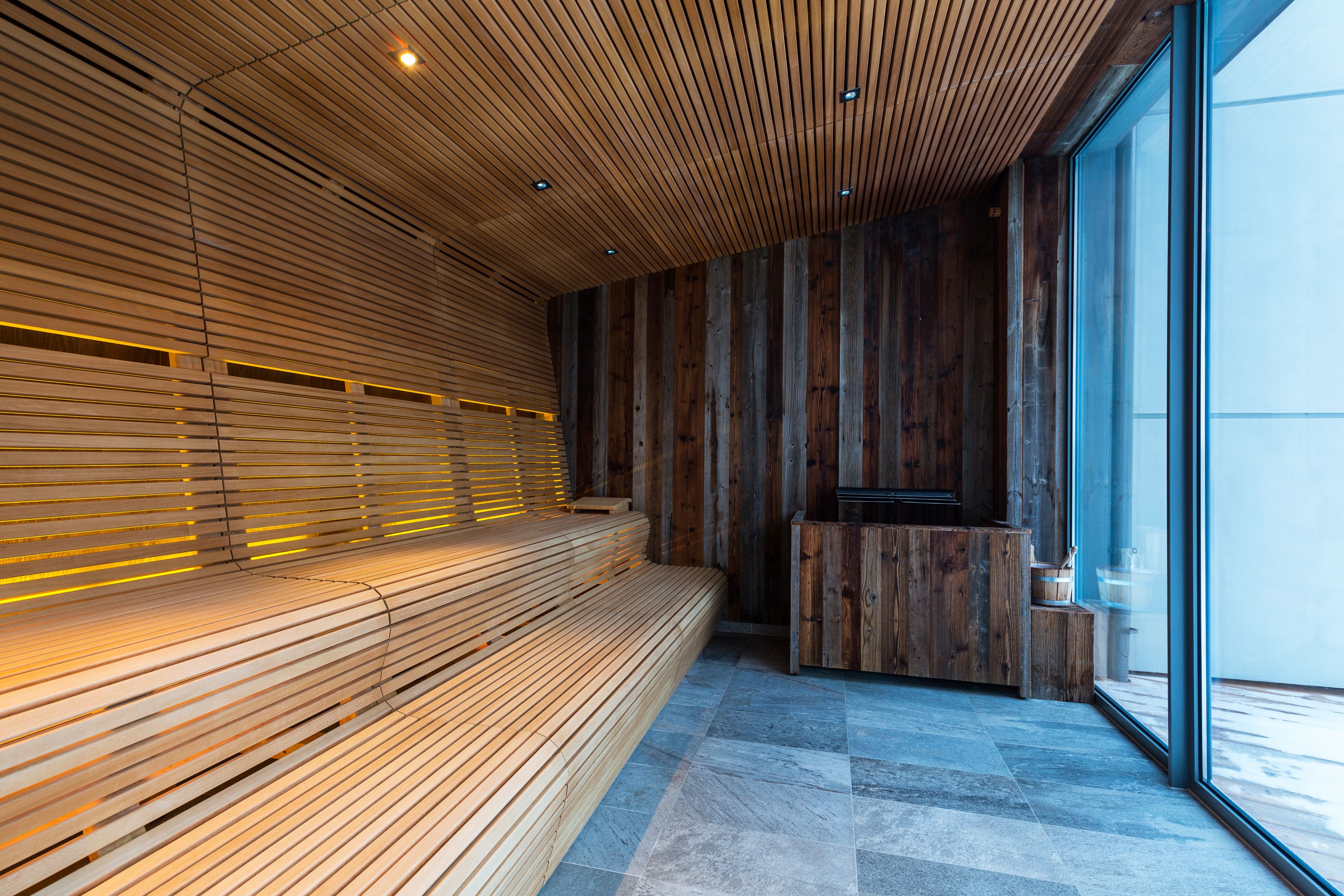 Un interior moderno con un banco de madera, una recepción y ventanas amplias.