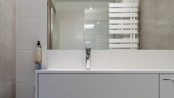 Een moderne badkamer met een wit badkamermeubel, een spiegel en een douchehoek.