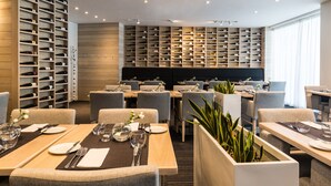 Un espace de restauration moderne, doté de plusieurs tables, de chaises et d’un grand meuble à vin.