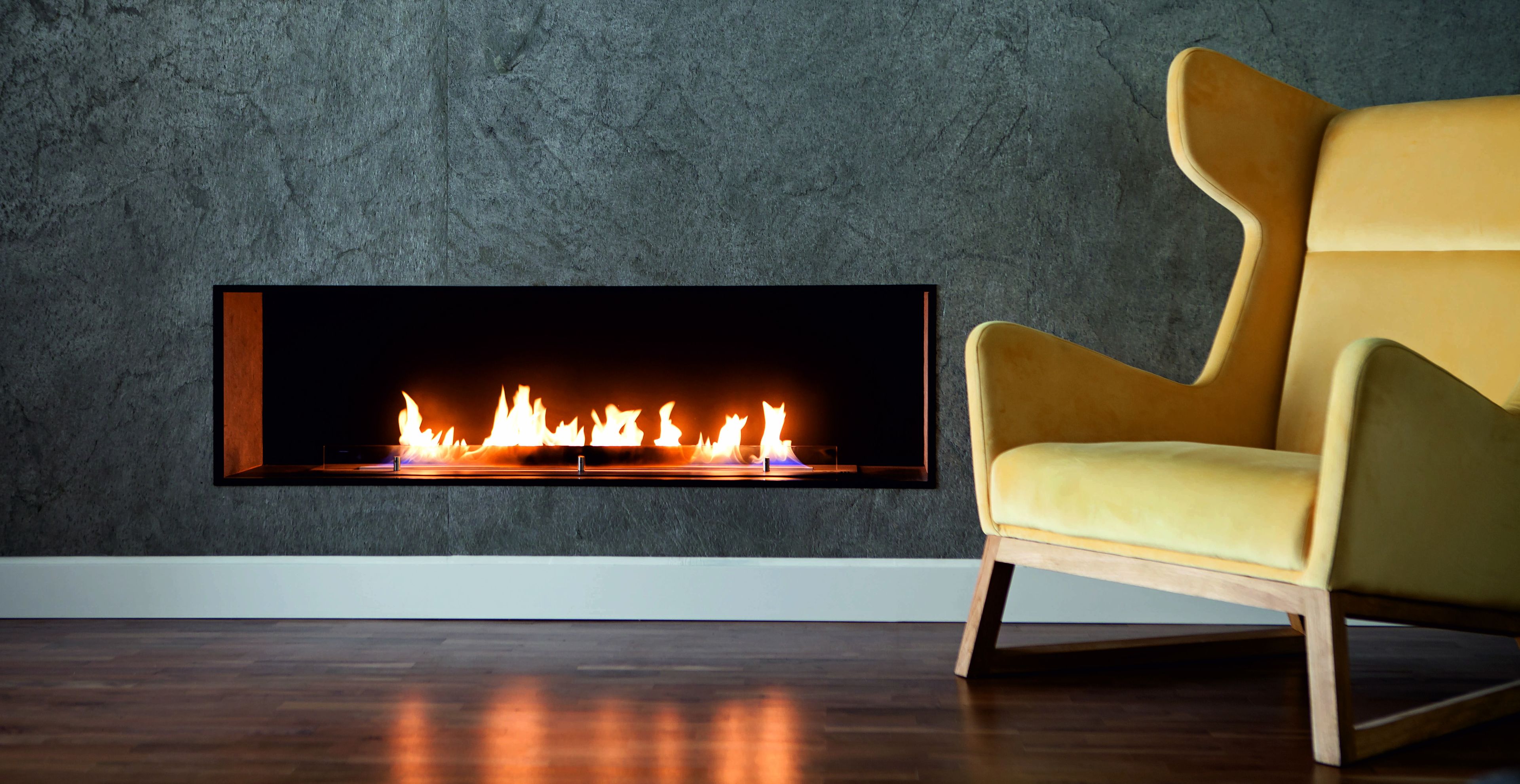 A modern living room with a built-in fireplace, a wooden floor, and a yellow armchair.