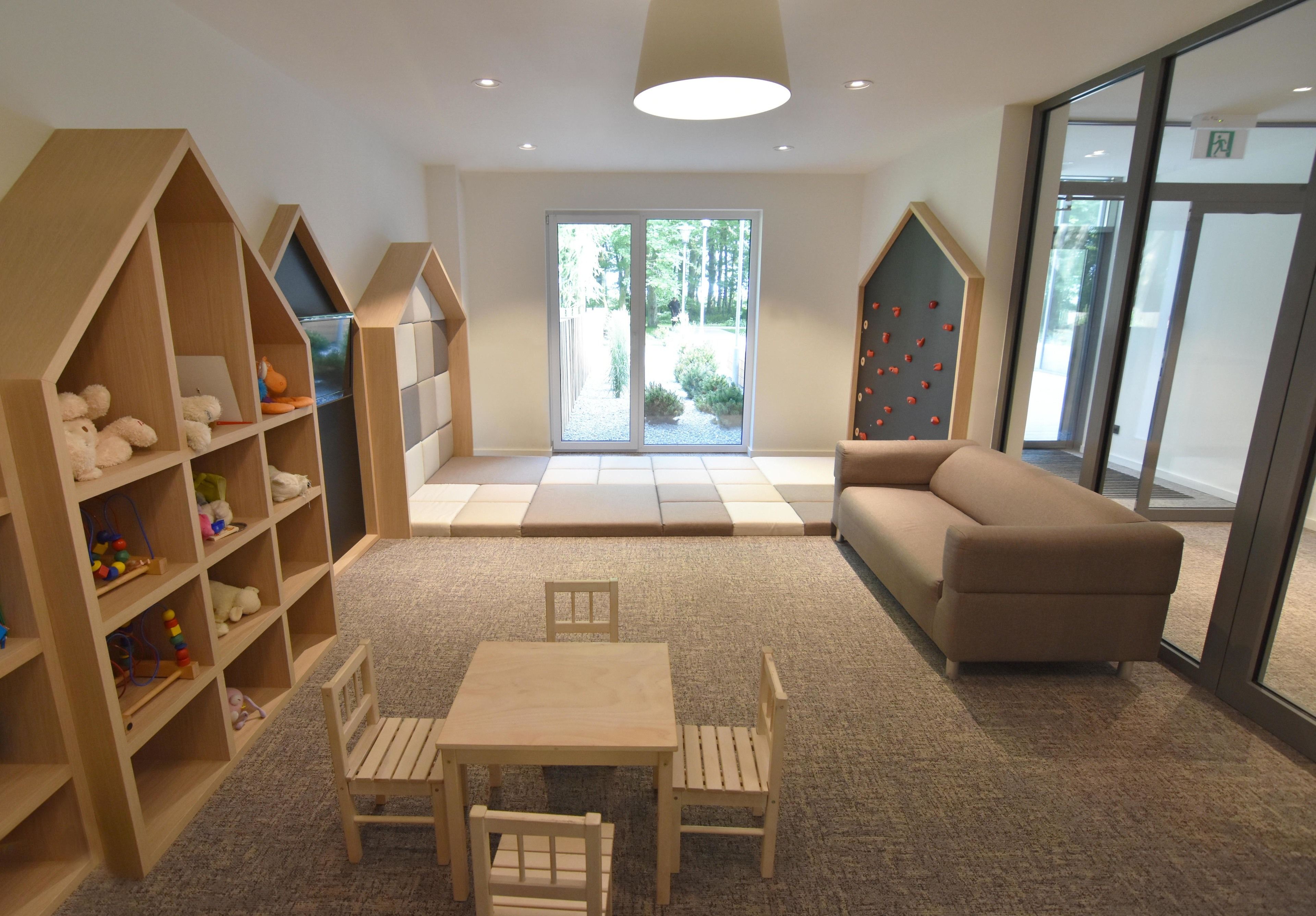 Ein kindgerechtes Zimmer mit Spielbereich, einer Couch und einem Tisch mit Stühlen.