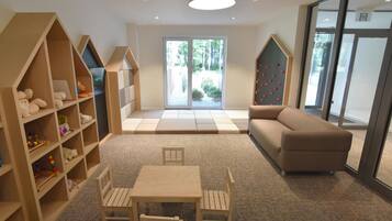 Ein kindgerechtes Zimmer mit Spielbereich, einer Couch und einem Tisch mit Stühlen.