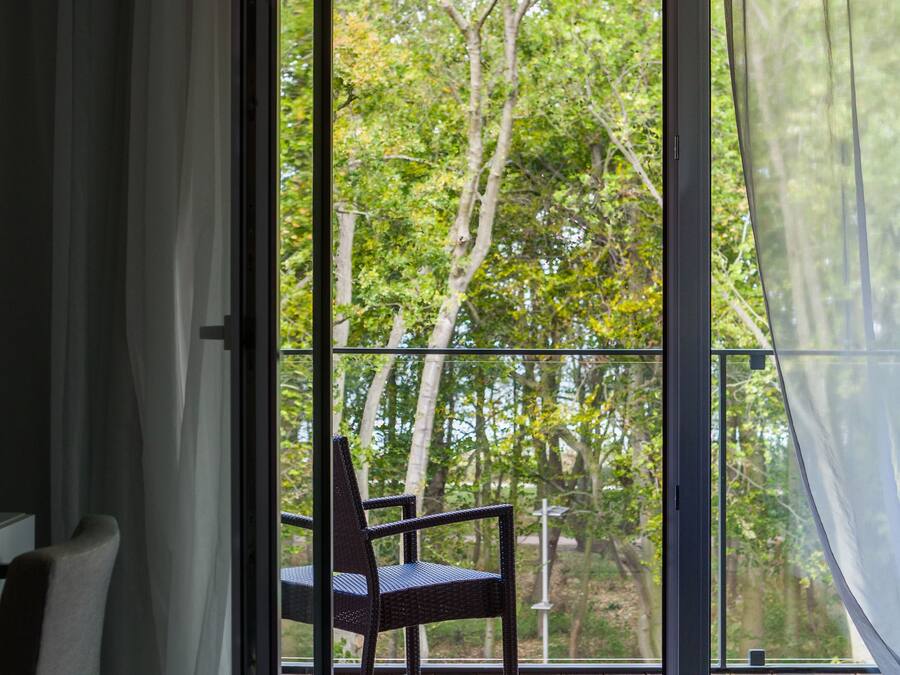 Una habitación con puerta de vidrio corredera que da a una terraza al aire libre con una silla.