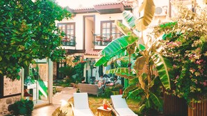 A courtyard with a wooden deck, lounge chairs, and a dining area with outdoor seating. - The Suite Apart Hotel Kaleiçi (Antalya)