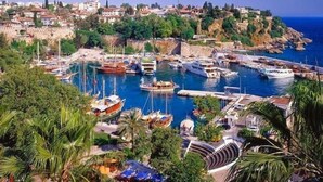 A coastal marina with boats docked, surrounded by lush greenery and residential buildings. - The Suite Apart Hotel Kaleiçi (Antalya)