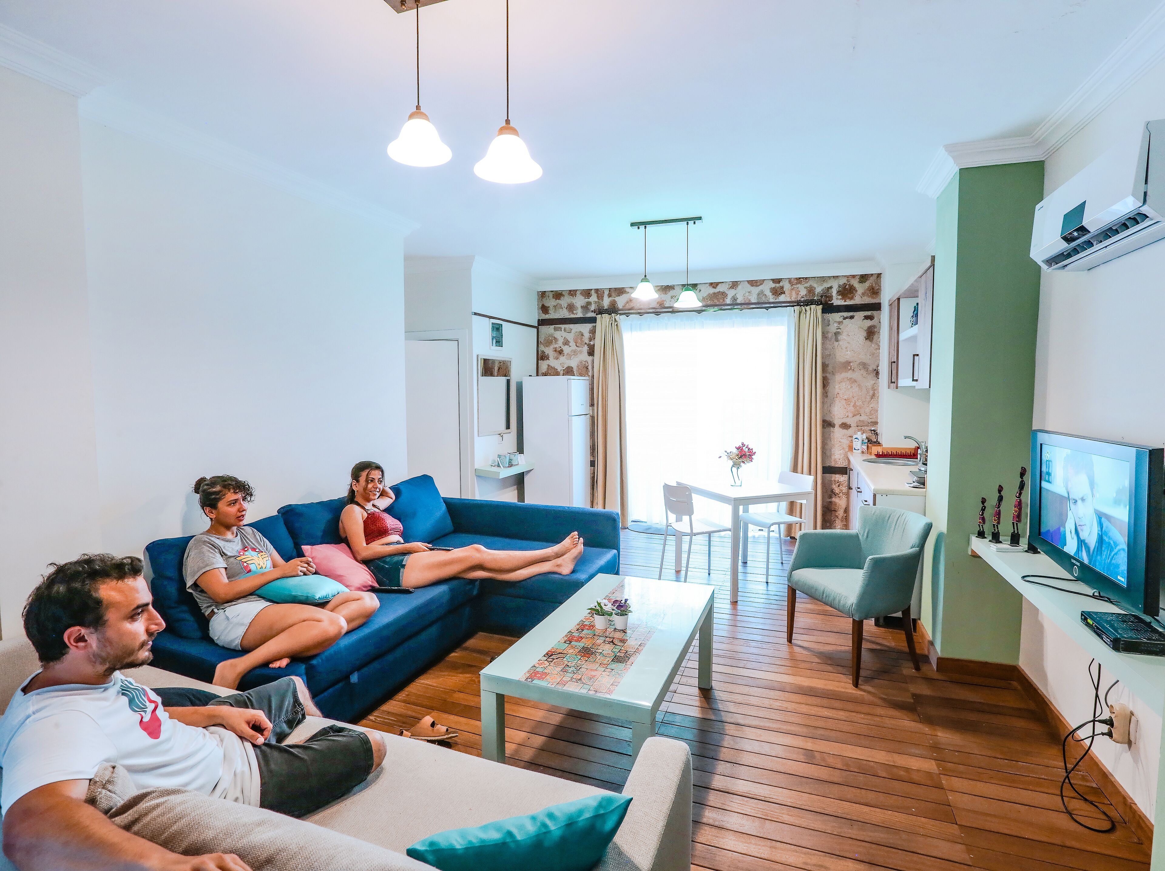 Una sala de estar con un sofá azul, una mesa de centro de madera y un televisor.