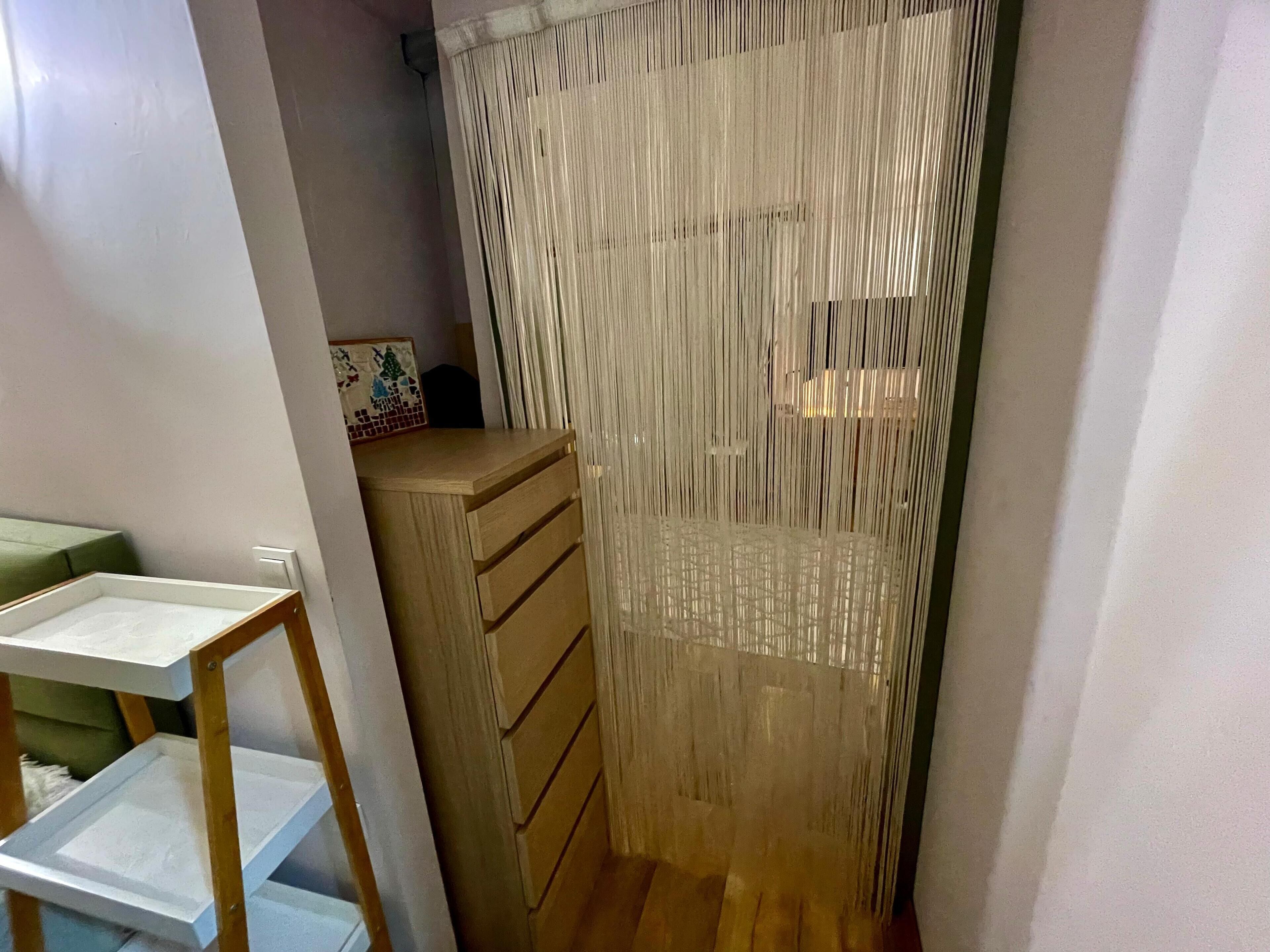 A narrow hallway with a wooden cabinet and a white shelf unit.