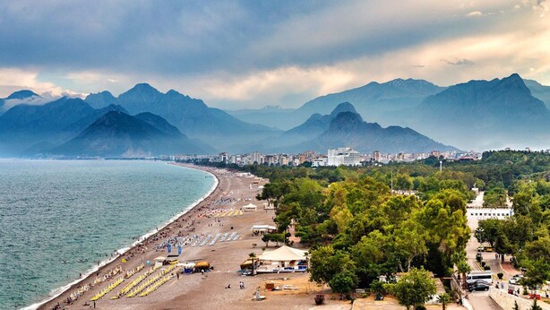 A coastal cityscape with a beach, mountains, and urban buildings. - The Suite Apart Hotel Kaleiçi (Antalya)