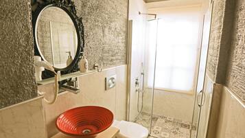 Un baño con pared de mármol, un lavamanos rojo, un inodoro y una zona de ducha.