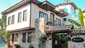 A two-story building with a stone facade, a balcony with wrought iron railings, and a sign indicating it is a hotel. - The Suite Apart Hotel Kaleiçi (Antalya)
