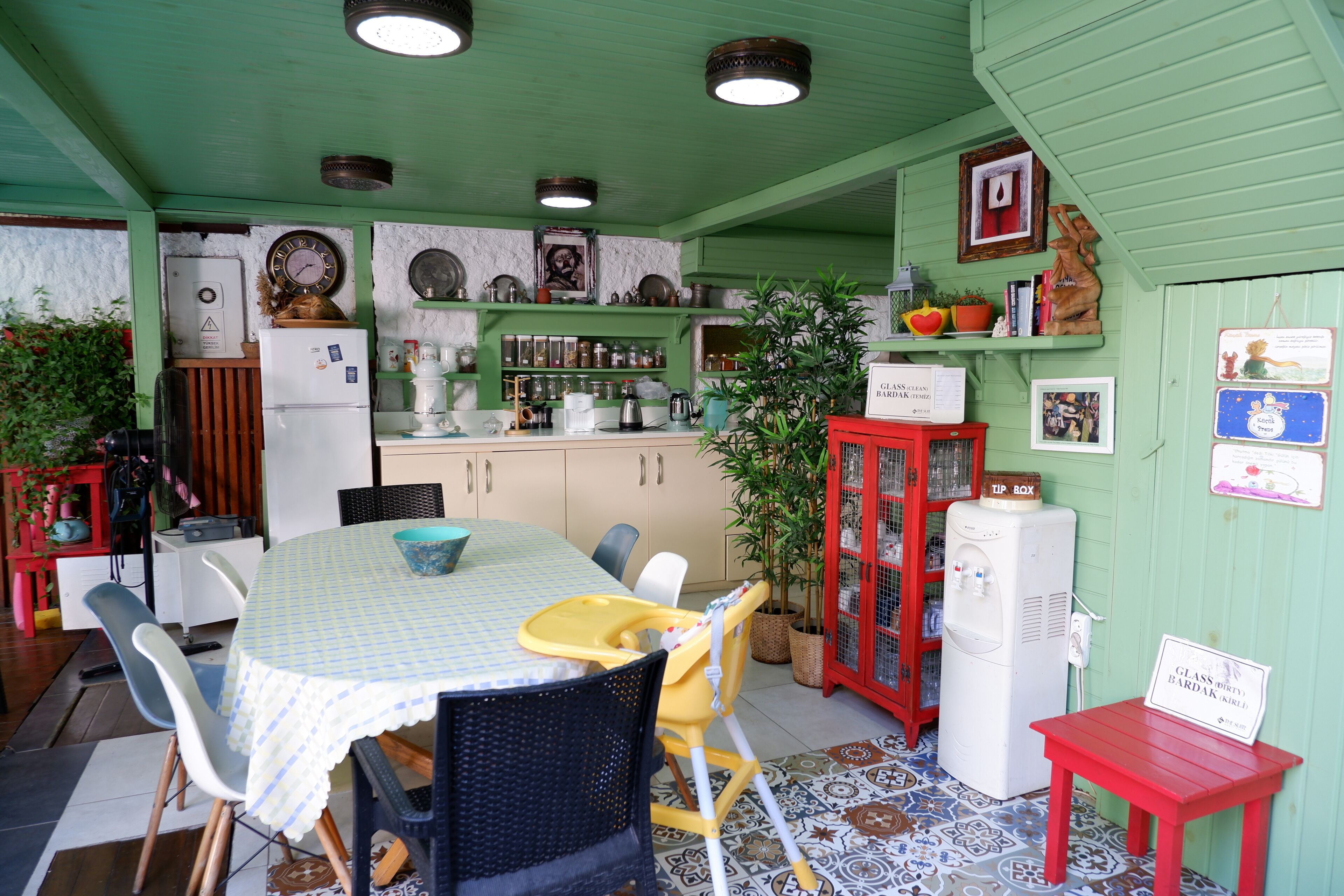 Une cuisine équipée d’une table à manger, de chaises, d’un réfrigérateur et de divers ustensiles de cuisine.