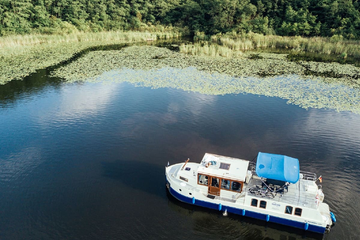 Ein Hausboot mit einer überdachten Deckfläche, Fenstern und einem kleinen Wohnbereich.