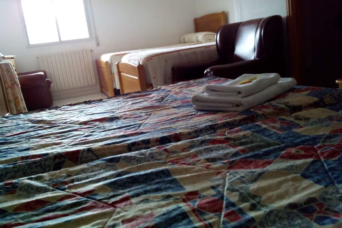 Een slaapkamer met een bed, een stoel, een bureau en een radiator.