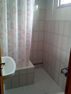 Een badkamer met douchegordijn, toilet en wastafel.