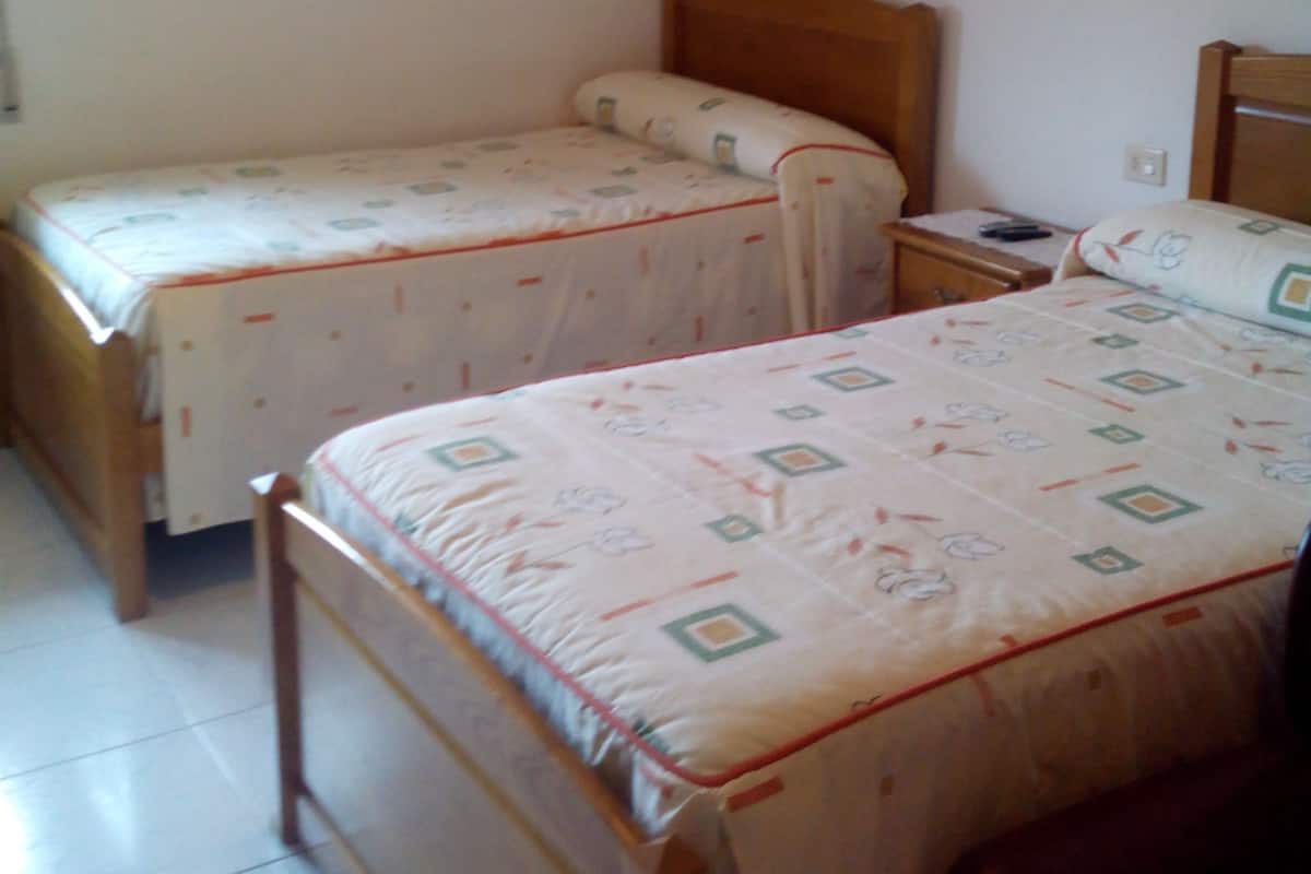Een slaapkamer met twee eenpersoonsbedden, elk met een houten hoofdbord en een bed met een patroon.