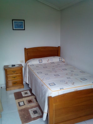 A small, neatly arranged bedroom with a single bed, a wooden nightstand, and a bedside table. - Hostal Sequeiros (San Cibrao Das Vinas)
