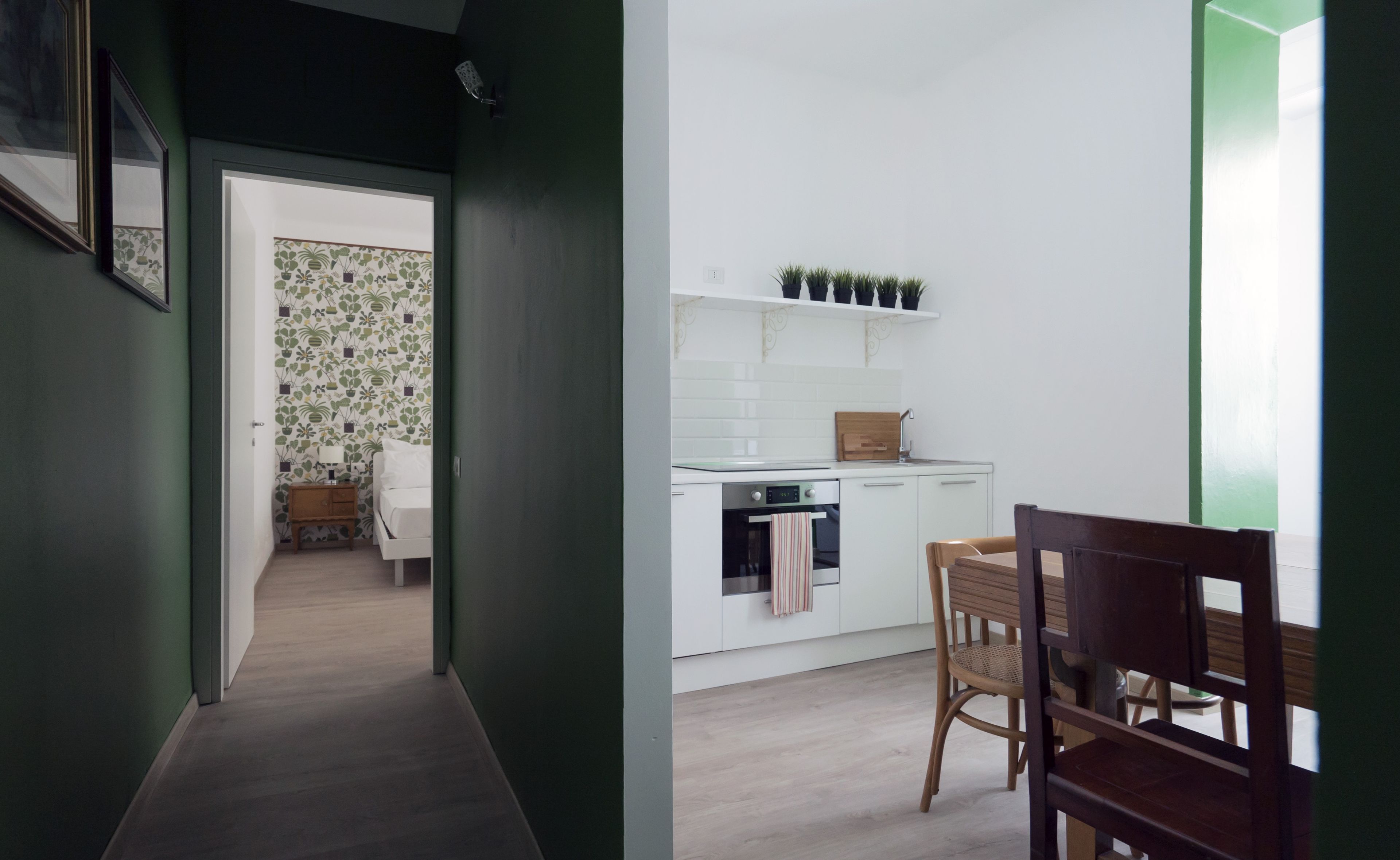 A modern kitchen with white cabinets, a wooden countertop, and a dining area with a wooden table and chairs.